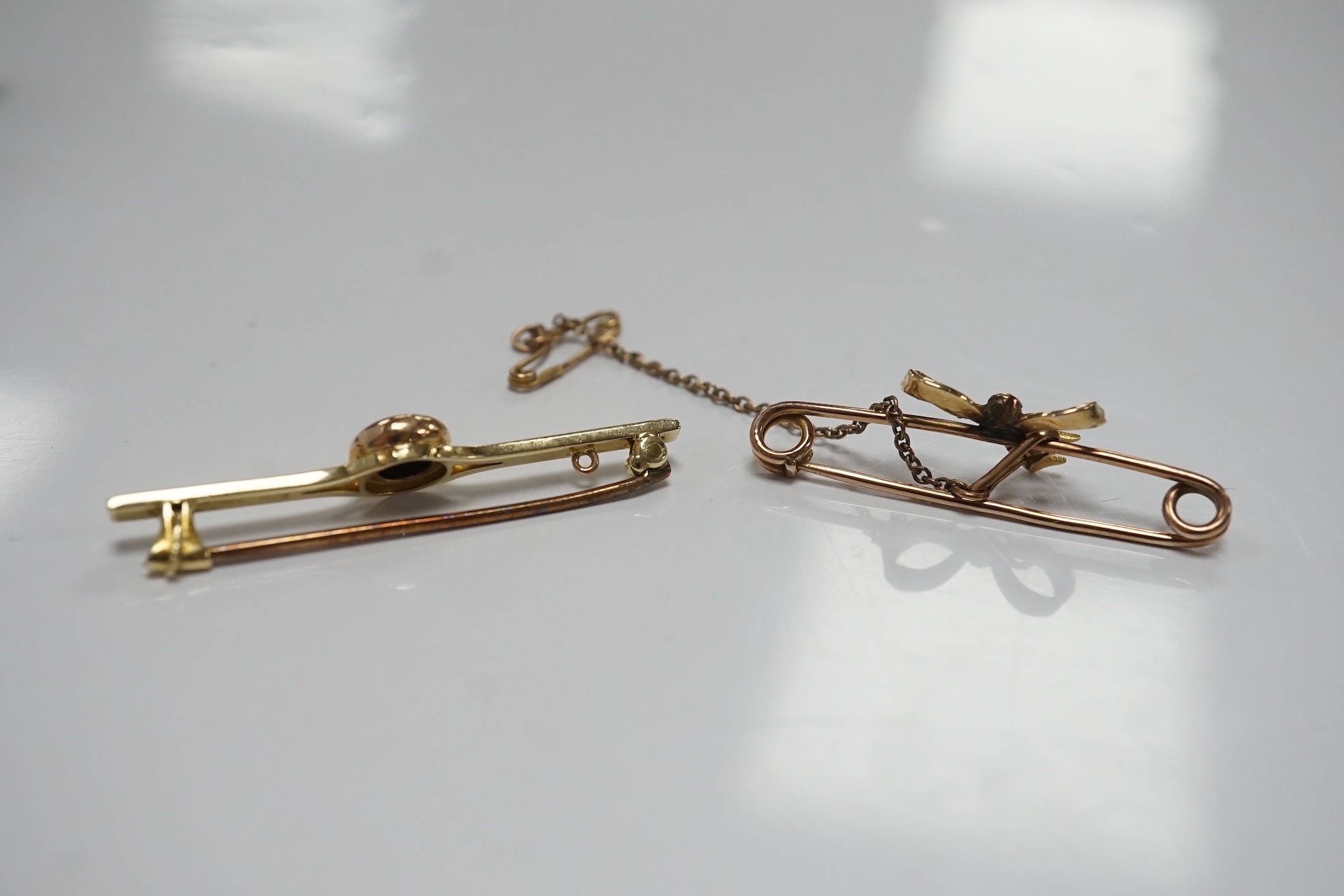 An early 20th century 15ct and solitaire diamond set bar brooch, 44mm, gross 3.5 grams and a similar 15ct, ruby and seed pearl set ribbon bow bar brooch, 2.4 grams. Condition - fair to good